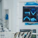 Close up of medical stomatology display with teeth x ray images on it. Empty professional hospital orthodontist chair with nobody in it. Close up revealing shot. Modern dentistry equipment